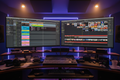 Rough cut timeline on DAW and video editor on dual monitors with cool studio lighting