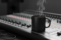 Minimalist black ceramic mug with studio logo on mixing console